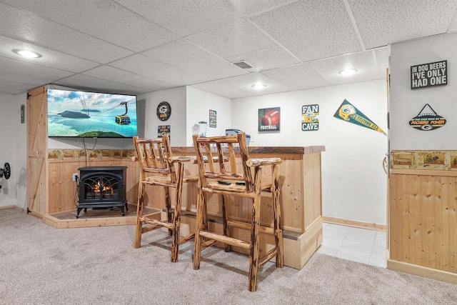 bar with visible vents, carpet, a bar, baseboards, and a wood stove