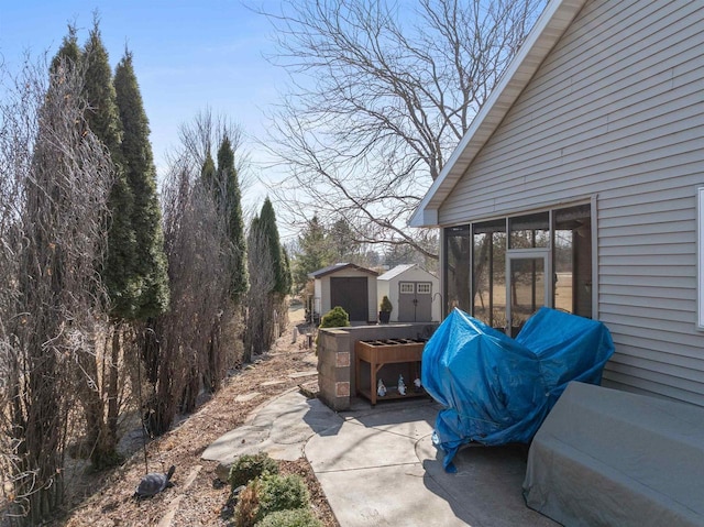 view of patio / terrace featuring an outbuilding, a sunroom, and a shed