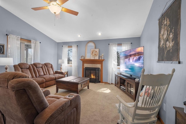 carpeted living room with a wealth of natural light, ceiling fan, a fireplace, and vaulted ceiling