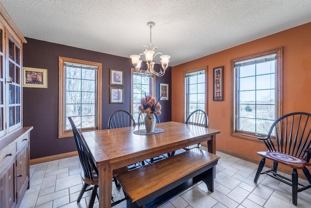 dining room featuring stone tile flooring, a notable chandelier, baseboards, and a textured ceiling