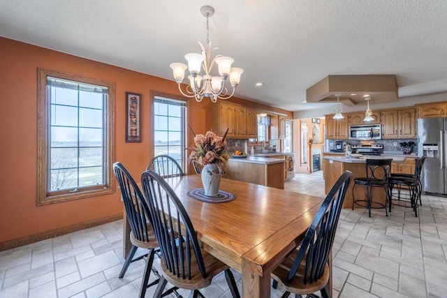 dining area featuring baseboards, recessed lighting, a textured ceiling, a raised ceiling, and a notable chandelier