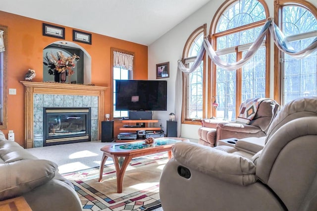 carpeted living room featuring a tiled fireplace and lofted ceiling