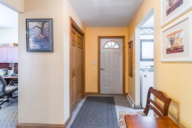 entryway with baseboards, a textured ceiling, washer / dryer, and tile patterned flooring