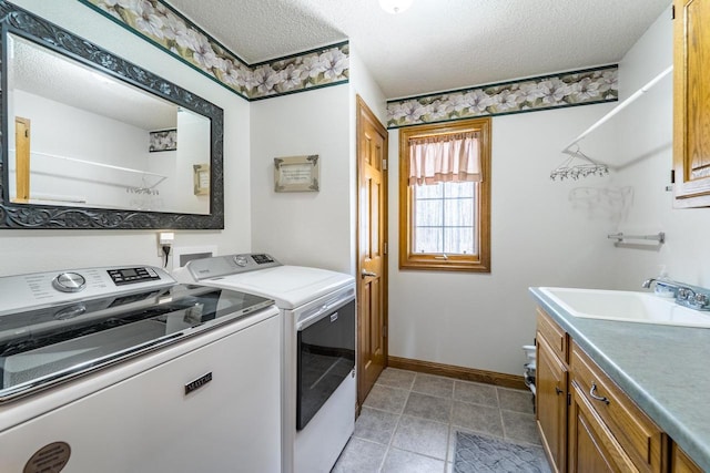 washroom with baseboards, washing machine and dryer, cabinet space, a textured ceiling, and a sink