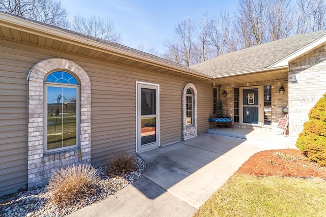 property entrance featuring a patio area and roof with shingles