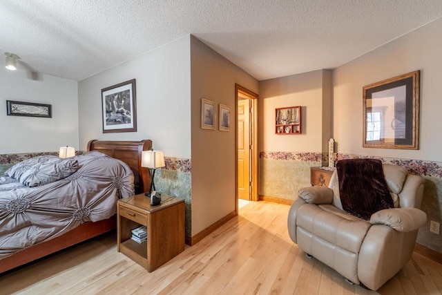 bedroom featuring baseboards, light wood finished floors, and a textured ceiling