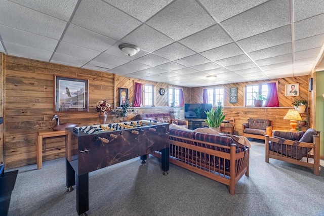 recreation room featuring a drop ceiling, plenty of natural light, wood walls, and carpet flooring