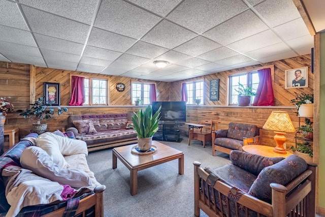 living room featuring a drop ceiling, carpet, and wood walls