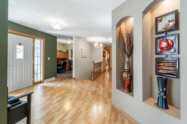 entrance foyer with baseboards, light wood finished floors, and a textured ceiling