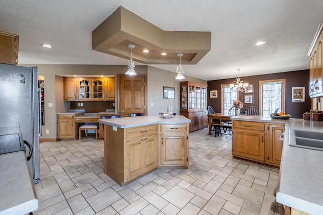 kitchen featuring glass insert cabinets, light countertops, hanging light fixtures, a notable chandelier, and a textured ceiling