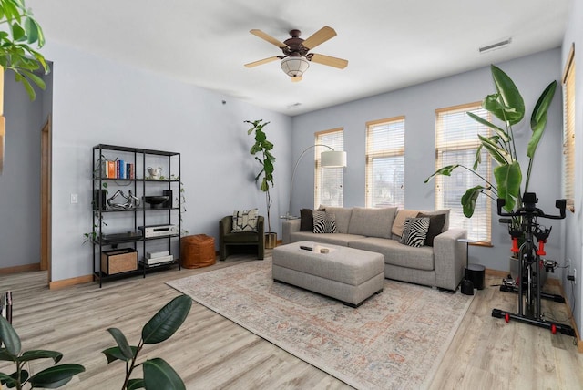 living room with ceiling fan, visible vents, baseboards, and wood finished floors