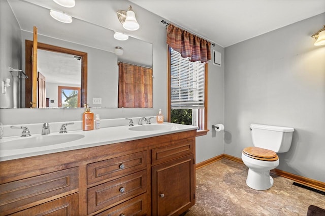 full bathroom with double vanity, toilet, baseboards, and a sink