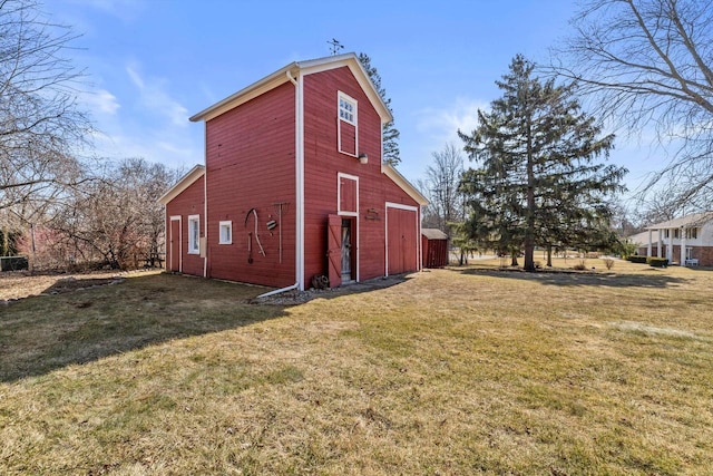 view of home's exterior with an outbuilding, a barn, and a lawn