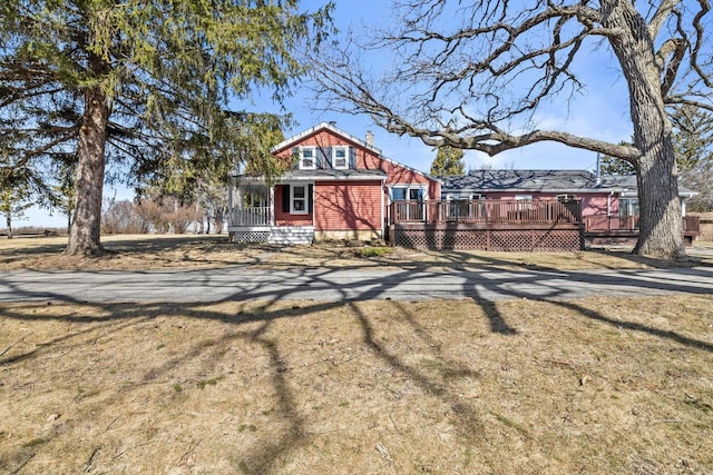 view of front facade with a wooden deck and a front lawn