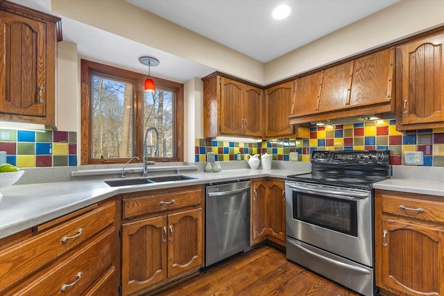 kitchen featuring under cabinet range hood, brown cabinets, appliances with stainless steel finishes, and a sink