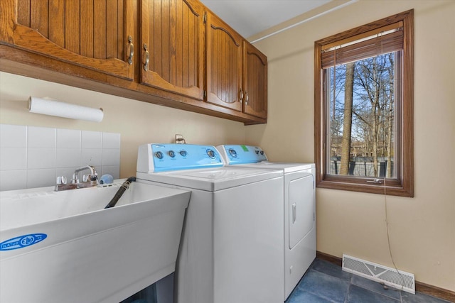 laundry area with visible vents, washer and clothes dryer, a sink, cabinet space, and baseboards