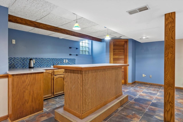 bar with baseboards, visible vents, stone finish floor, backsplash, and indoor bar