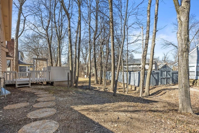 view of yard featuring an outbuilding, fence, a shed, and a wooden deck