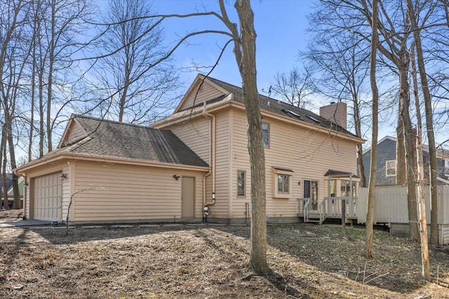 view of side of home featuring a garage, roof with shingles, and a chimney