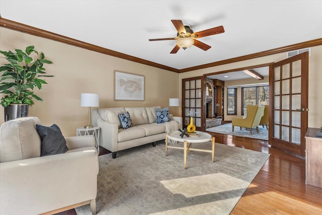 living room with a ceiling fan, wood finished floors, french doors, and ornamental molding