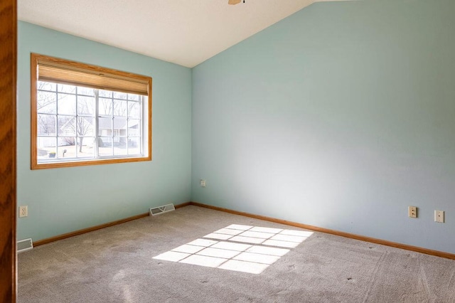 carpeted spare room with vaulted ceiling, baseboards, and visible vents