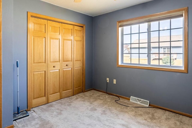 unfurnished bedroom with visible vents, baseboards, a closet, and carpet flooring