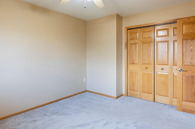 unfurnished bedroom with baseboards, carpet floors, a closet, and a ceiling fan