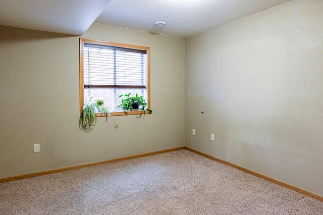 carpeted empty room with baseboards and a textured ceiling