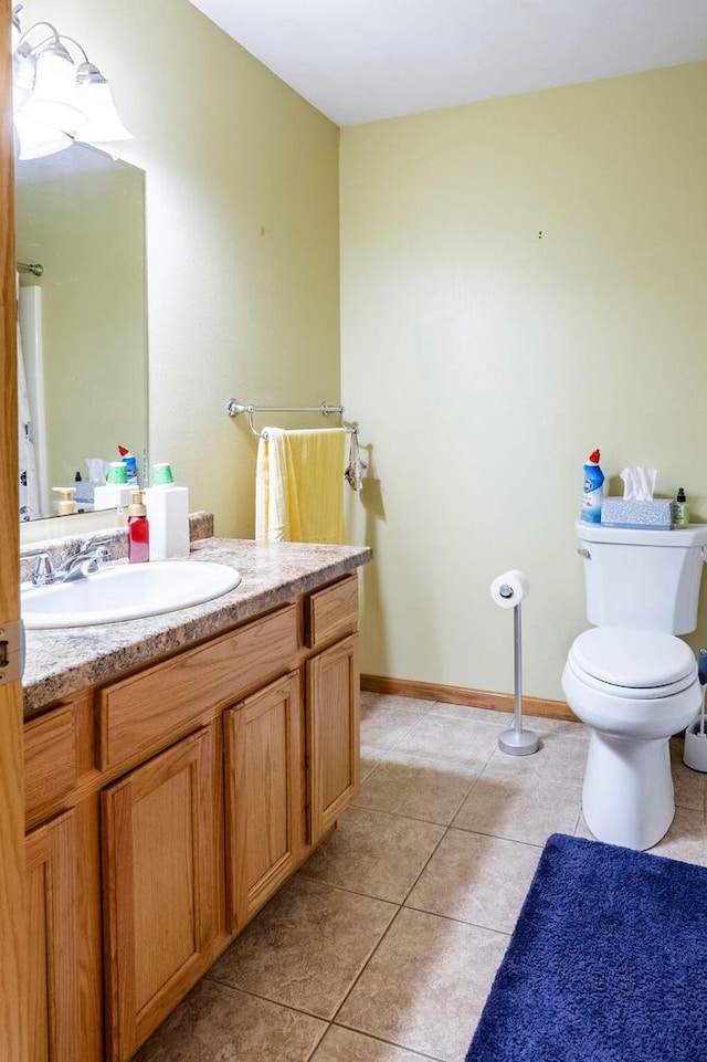 half bathroom featuring tile patterned flooring, toilet, vanity, and baseboards