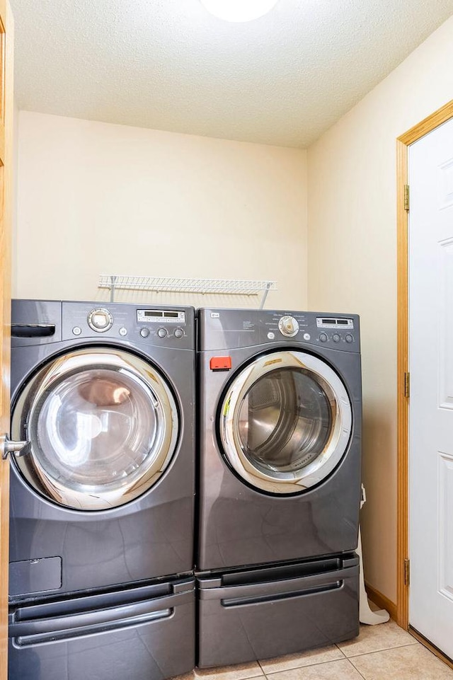 laundry room featuring laundry area, independent washer and dryer, tile patterned floors, and a textured ceiling