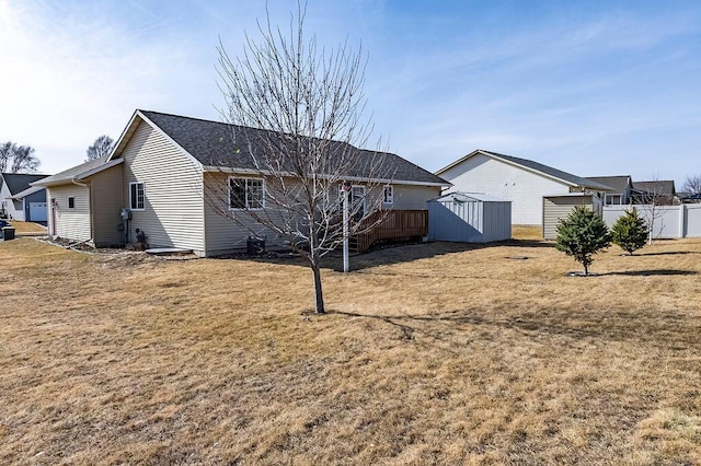 back of house featuring a lawn, a storage shed, an outdoor structure, and fence