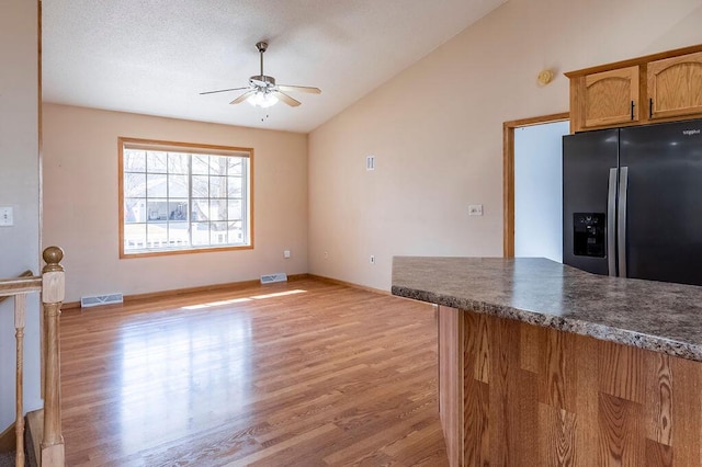 kitchen featuring visible vents, ceiling fan, fridge with ice dispenser, and vaulted ceiling