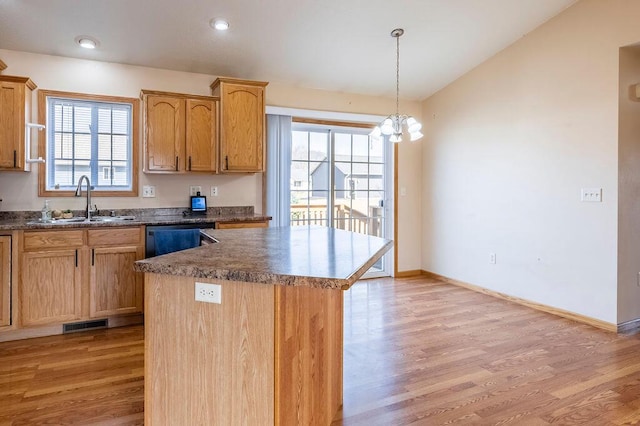 kitchen with a sink, baseboards, light wood-style floors, dishwashing machine, and lofted ceiling