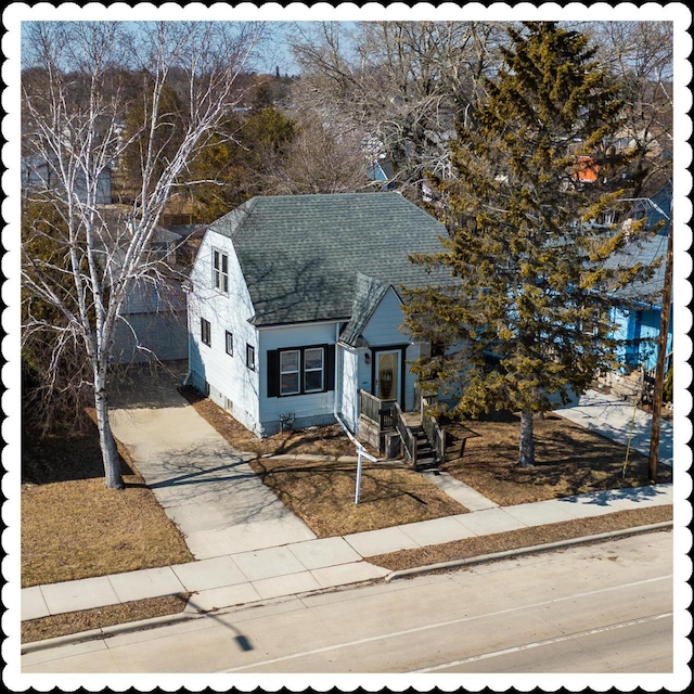 view of front facade with driveway and a shingled roof