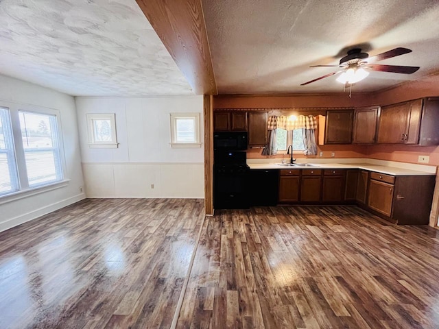 kitchen featuring black appliances, a sink, a textured ceiling, ceiling fan, and dark wood-style flooring