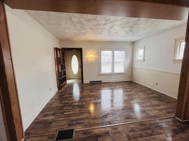 entrance foyer featuring visible vents, a textured ceiling, and dark wood-type flooring