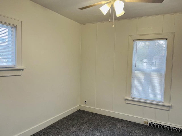 spare room with dark colored carpet, visible vents, baseboards, and a ceiling fan