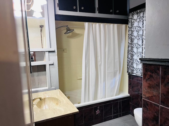 full bathroom featuring tiled shower / bath, toilet, tile walls, and vanity