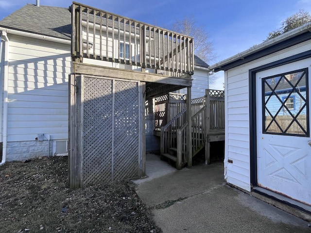 exterior space with a wooden deck, stairs, and a shingled roof