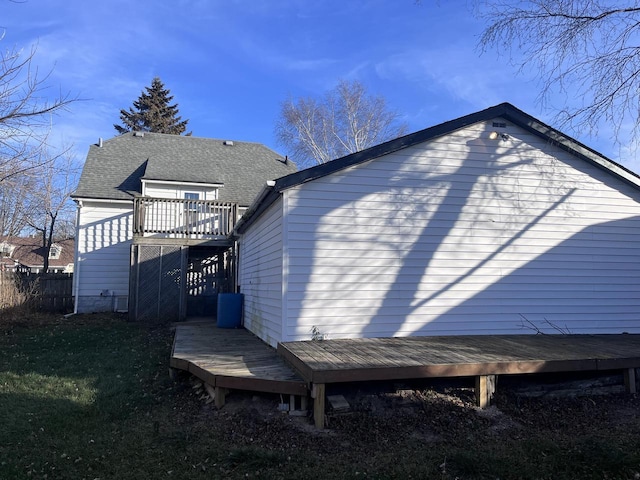 rear view of house featuring a deck and roof with shingles