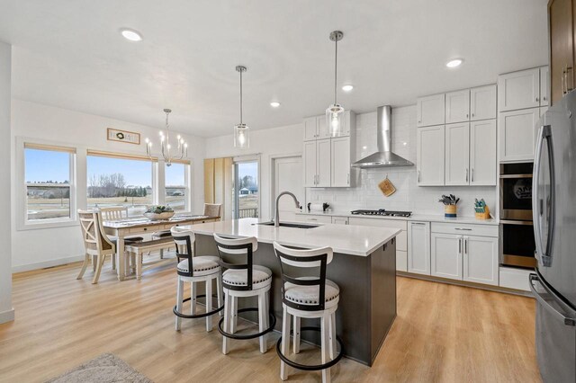 655 Sunset Grn, Bay, WI 54313 - kitchen with tasteful backsplash, light countertops, appliances with stainless steel finishes, wall chimney exhaust hood, and a sink