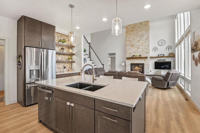 655 Sunset Grn, Bay, WI 54313 - kitchen featuring an island with sink, a sink, stainless steel appliances, dark brown cabinetry, and a fireplace