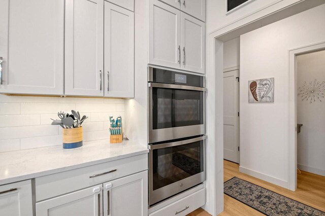 655 Sunset Grn, Bay, WI 54313 - kitchen featuring double oven, light stone counters, tasteful backsplash, and light wood finished floors