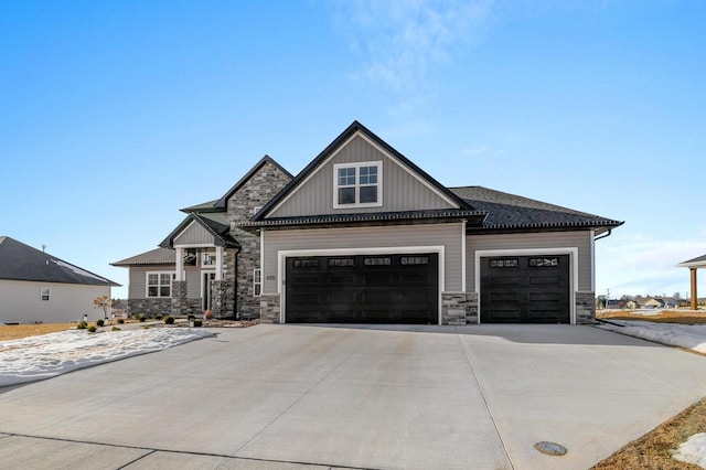 craftsman-style home with board and batten siding, an attached garage, stone siding, and driveway