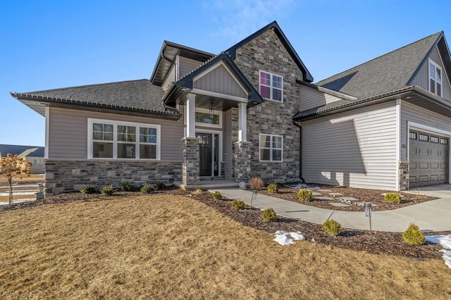 craftsman-style home featuring an attached garage, fence, and stone siding