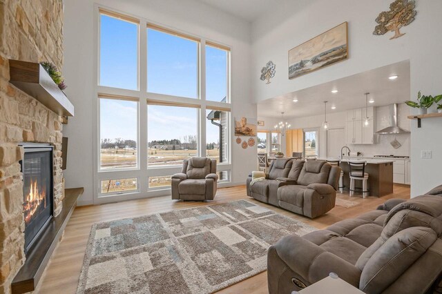 655 Sunset Grn, Bay, WI 54313 - living room featuring a high ceiling, a fireplace, light wood-style floors, and a chandelier