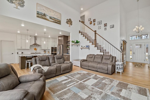 655 Sunset Grn, Bay, WI 54313 - living room featuring a notable chandelier, stairs, light wood-type flooring, and a towering ceiling