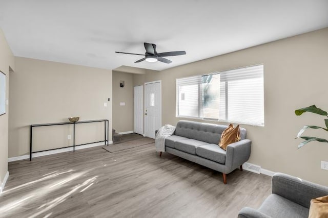 living room featuring visible vents, baseboards, a ceiling fan, and wood finished floors