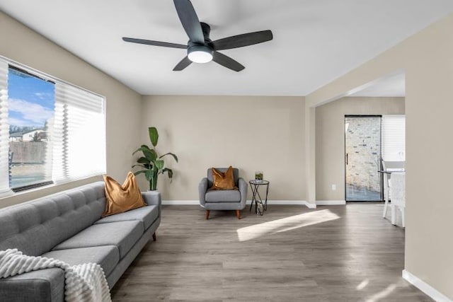 living room featuring baseboards, ceiling fan, and wood finished floors