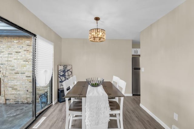 dining space with a notable chandelier, baseboards, and wood finished floors